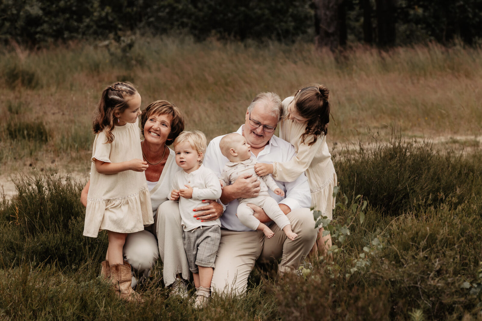 Opa en oma met de kleinkinderen op schoot. Niet perfect, maar wel met echte lachjes. Familieshoot met 3 generaties.