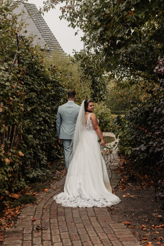 Bruid kijkt glimlachend achterom terwijl ze met haar partner wegloopt