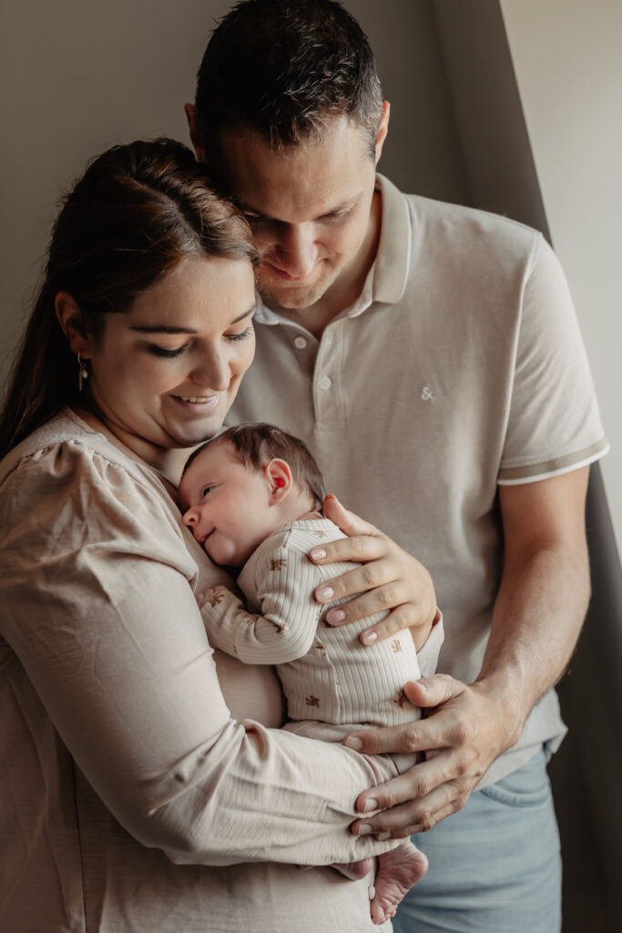 ouders met pasgeboren baby tijdens newbornshoot thuis – beste leeftijd newbornshoot