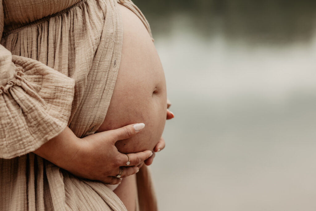 zwangere vrouw met handen op buik – zwangerschapsfoto en newbornshoot combinatie
