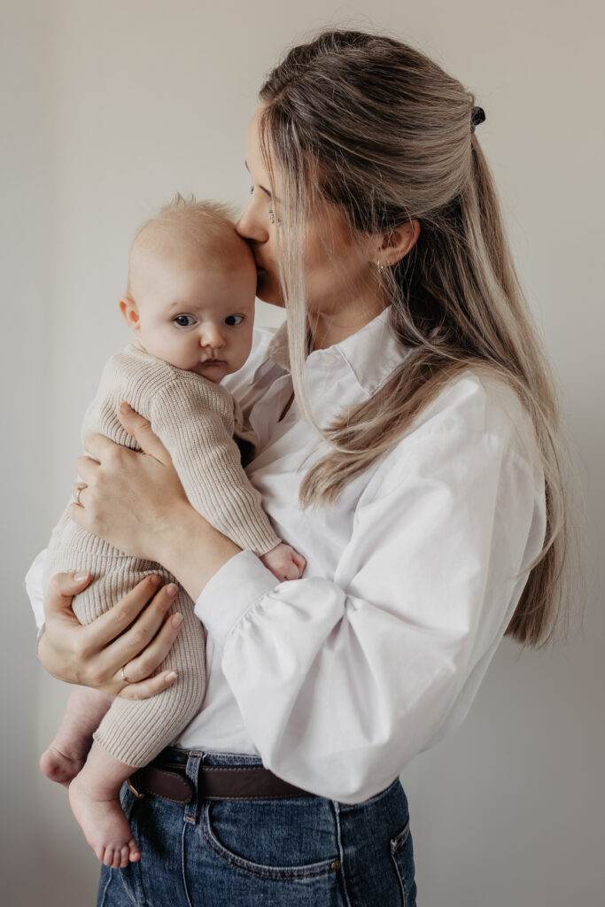 Moeder met newborn bij het raam tijdens newbornshoot in Baarle-Nassau