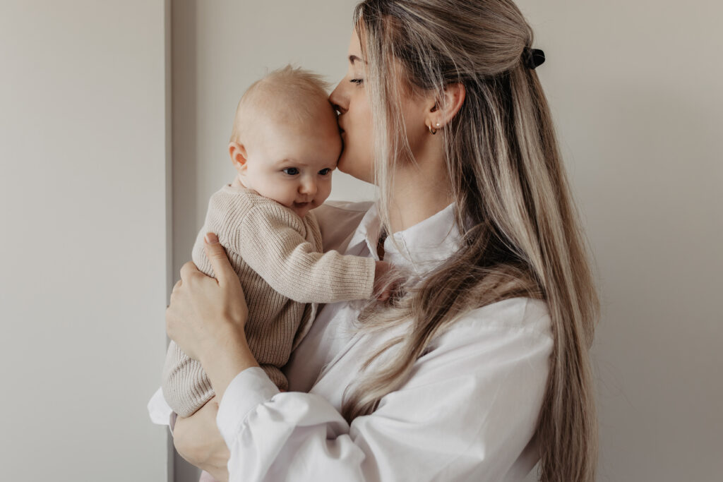 Mama geeft haar newborn een kus tijdens newbornshoot Baarle-Nassau